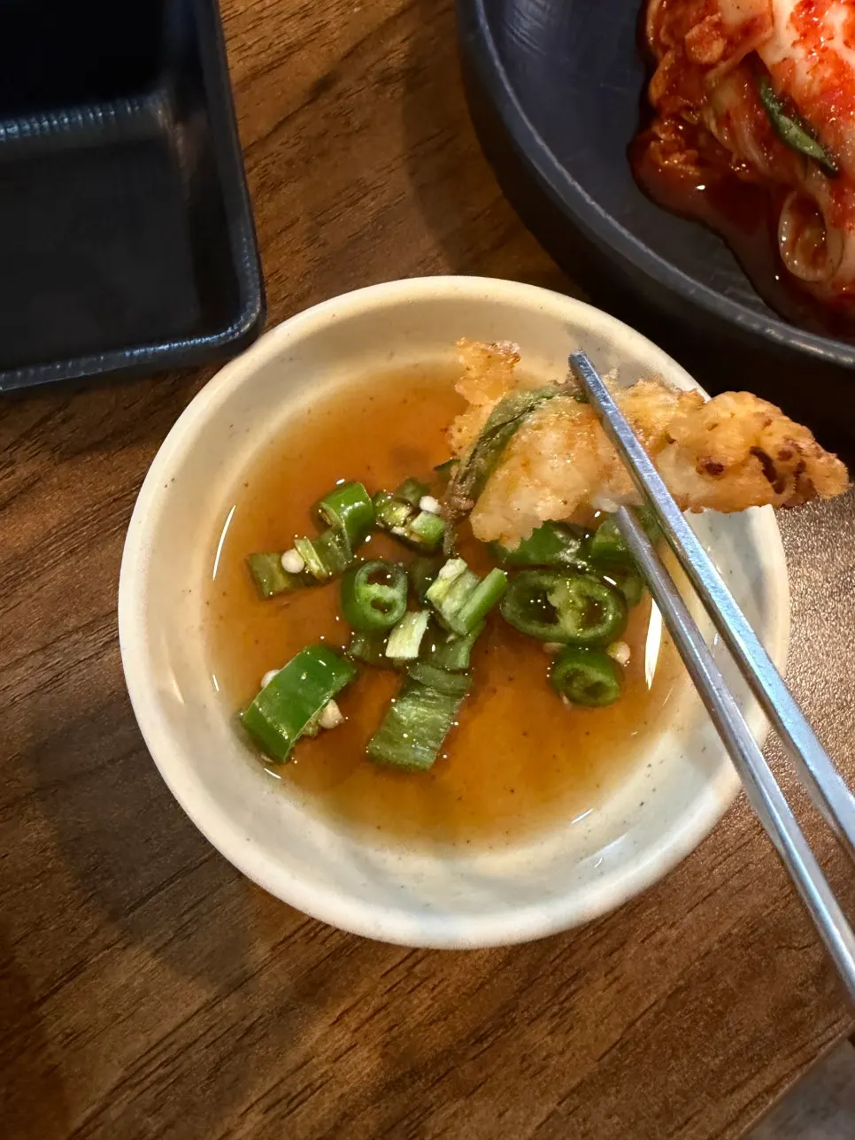 A piece of seafood pajeon lifted with chopsticks