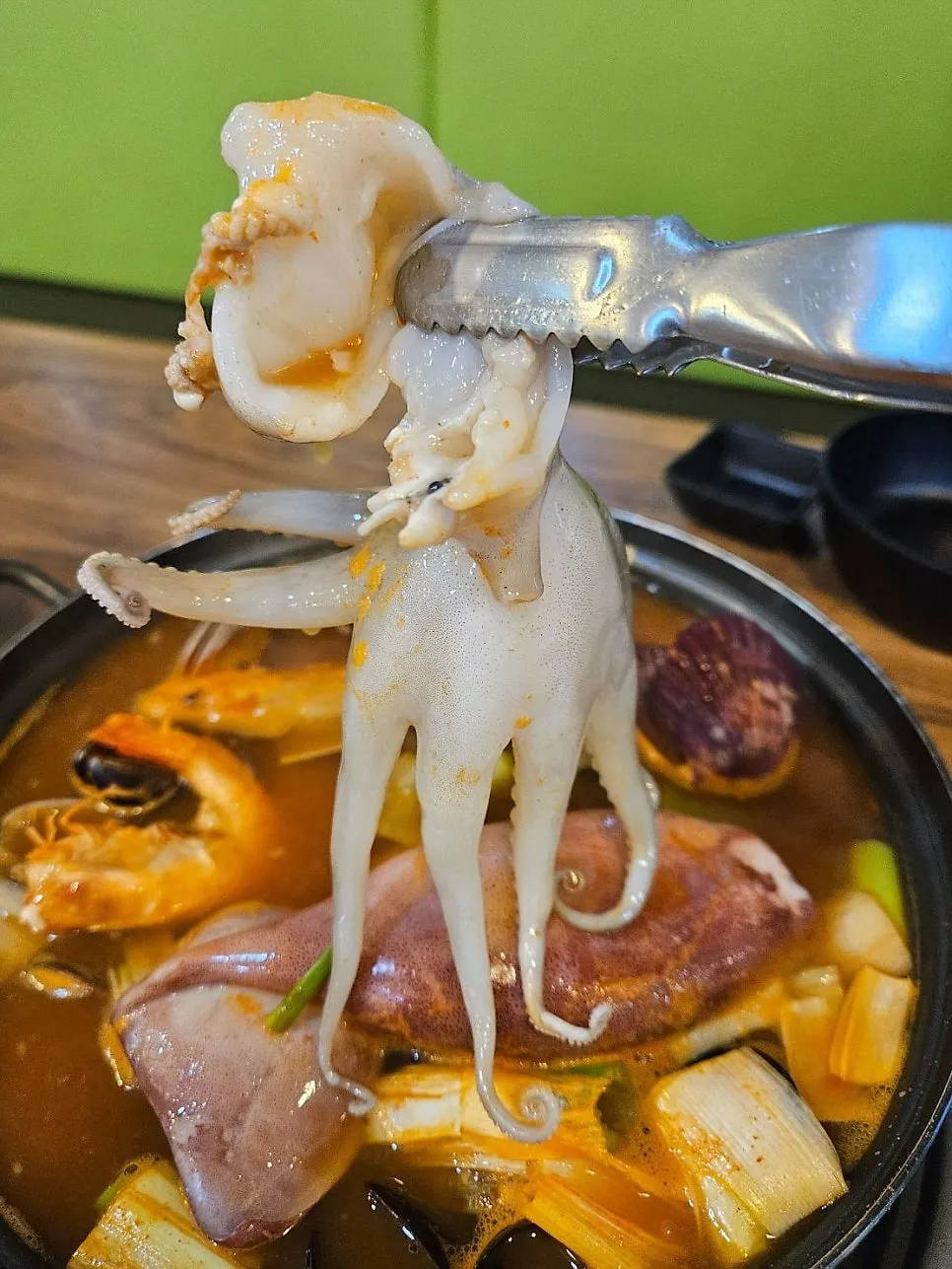 Pot of spicy seafood hand-cut noodle soup piled high with seafood