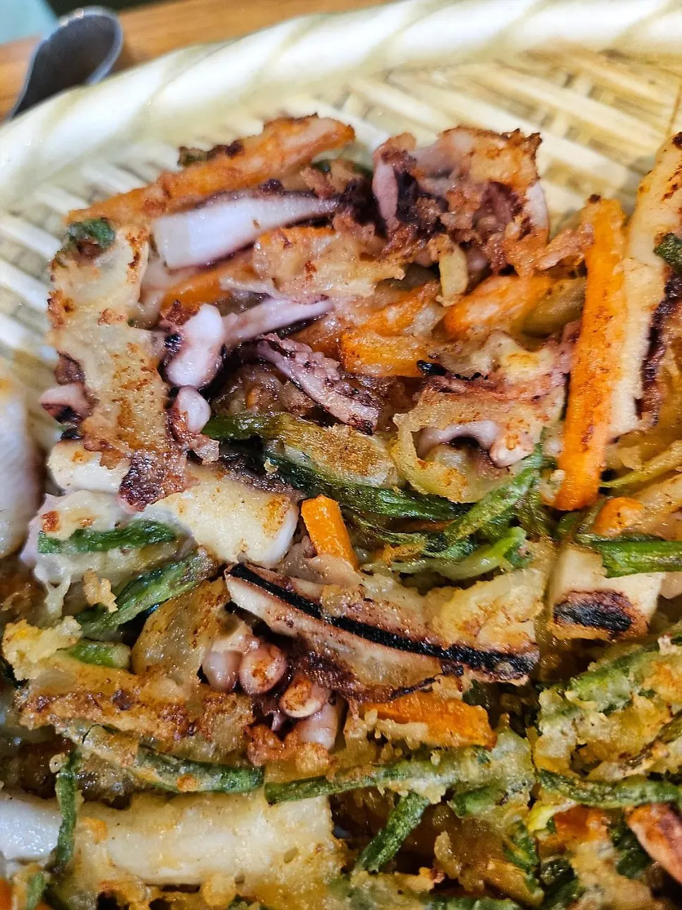 A piece of seafood pancake packed with green onion and seafood