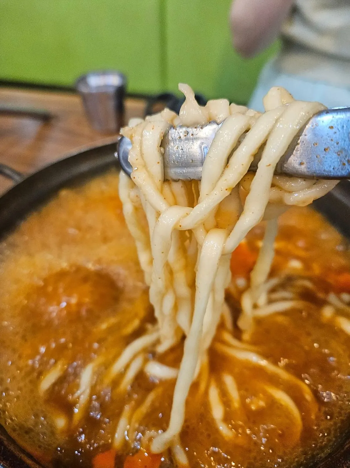 Chopsticks lifting a piece of the giant seafood pancake