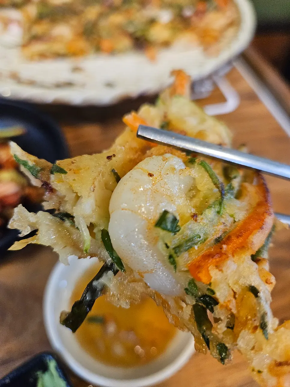 A bowl of seafood kalguksu broth served with cabbage kimchi