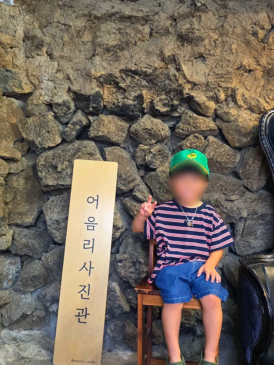 Polaroid and film cameras displayed on a Jeju stone wall
