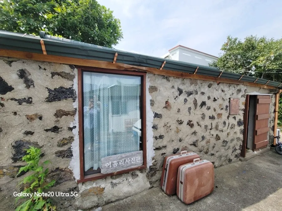 Vintage travel suitcase and window beneath a Jeju stone wall