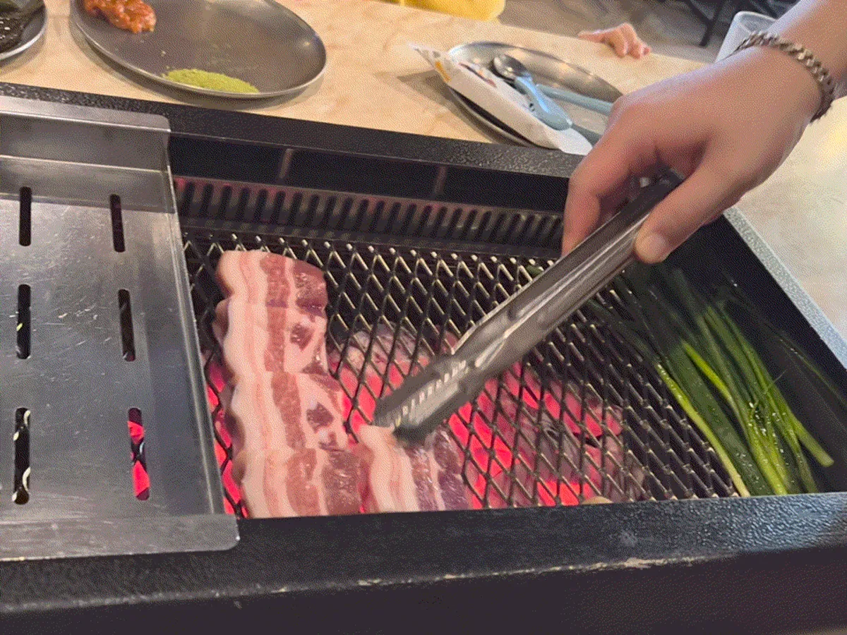 Staff grilling Jeju black pork on the tabletop grill