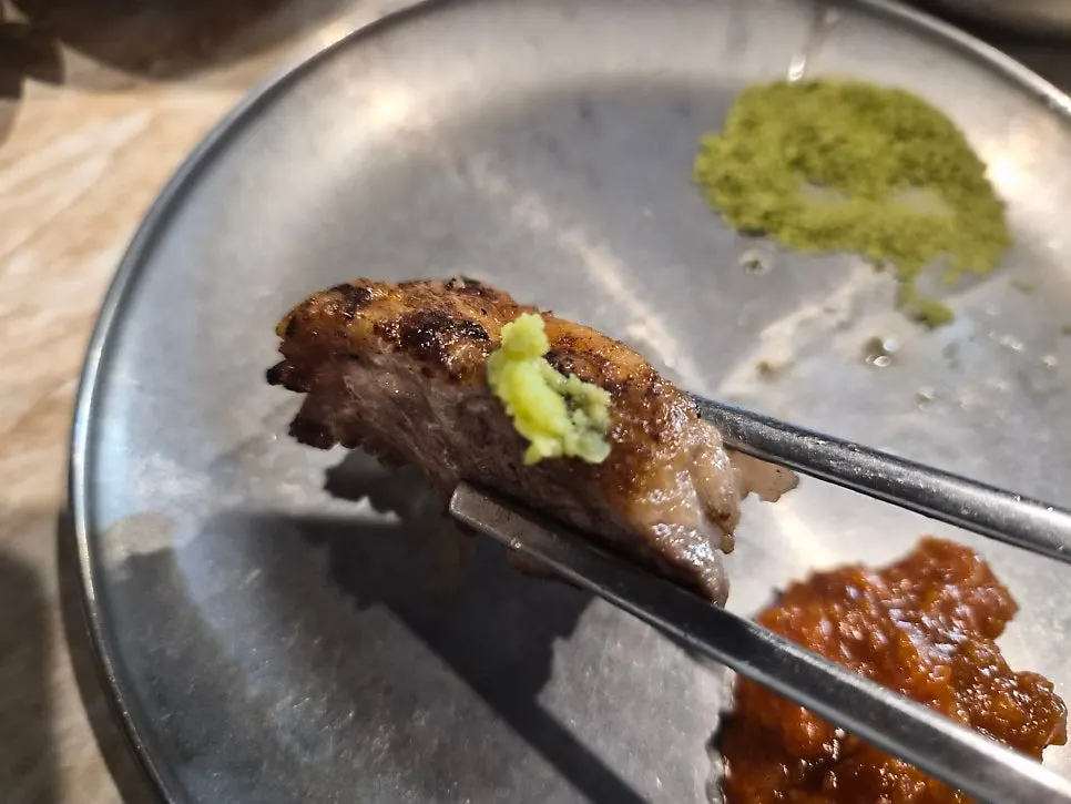 A piece of black pork dipped in matcha salt