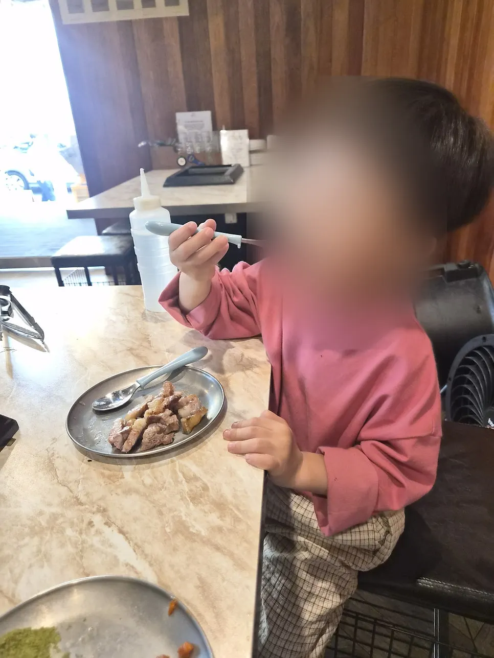 Table with a kid's rice bowl and black pork