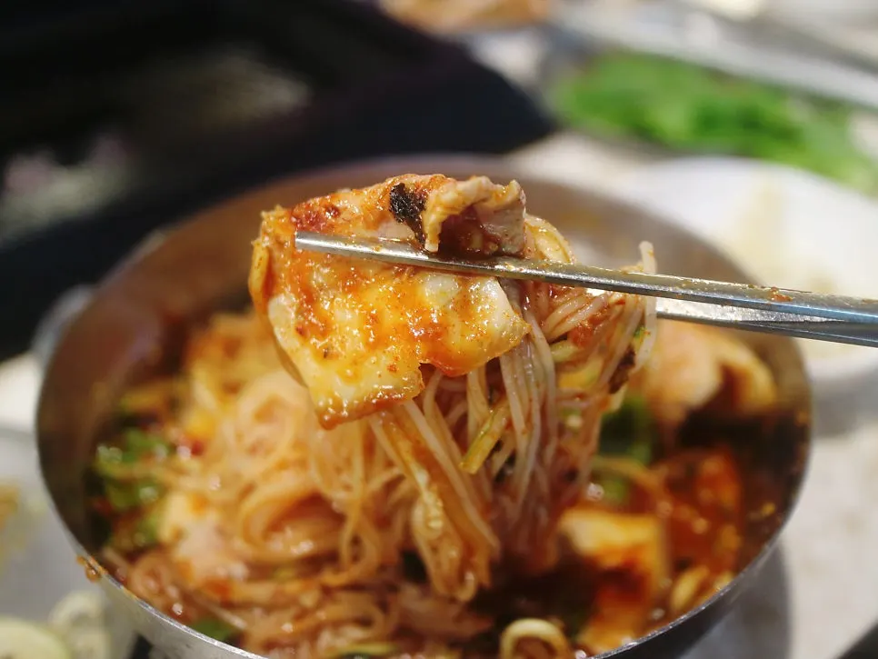 비빔국수에 고기 한 점을 올린 모습