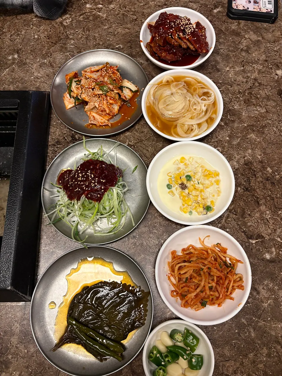Side dishes including scallion shreds, radish salad, and seasoned raw crab at Pork80