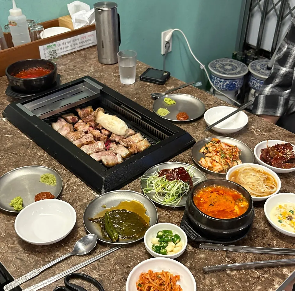 Table spread with sundubu-jjigae served alongside the meat