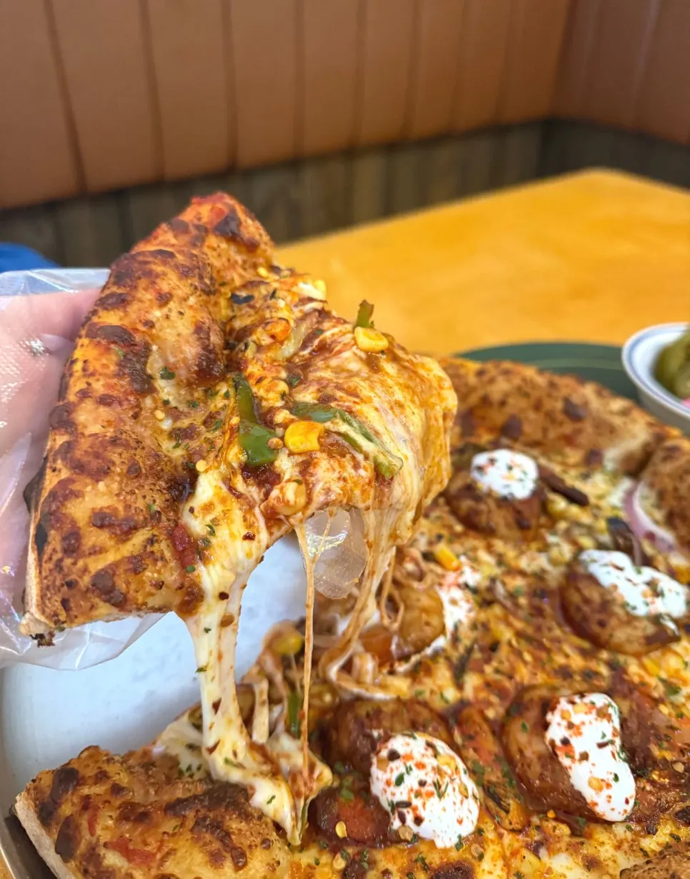 A slice of pizza topped with shrimp and sour cream sauce