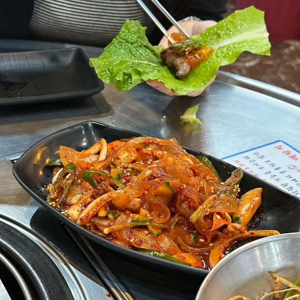A lettuce wrap topped with meat and dangmyeon-oi-muchim