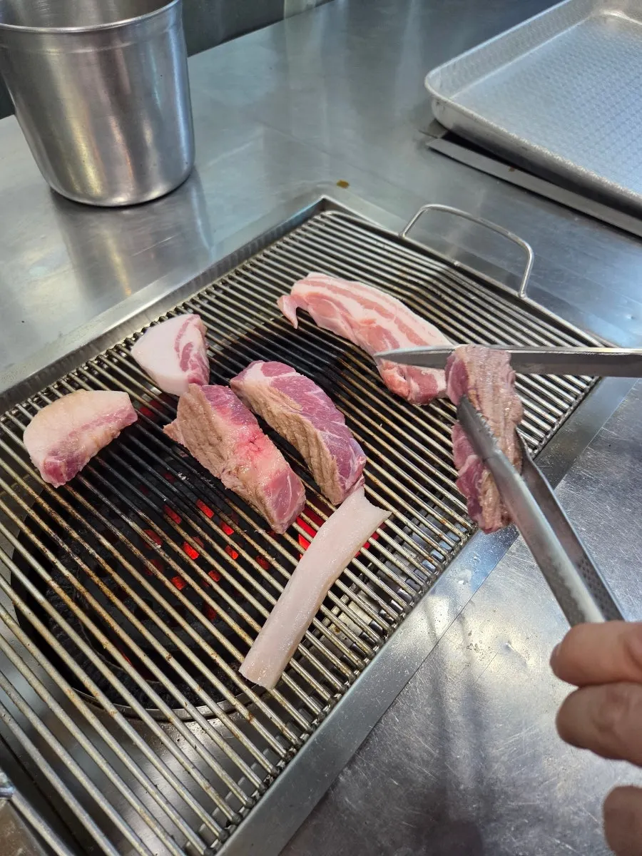 The owner pre-grilling black pork cut by cut