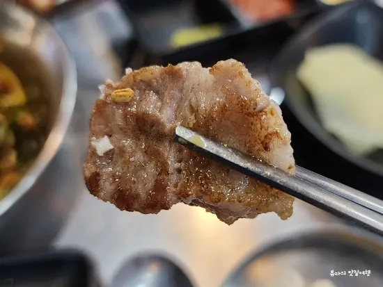A piece of black pork neck meat picked up with chopsticks