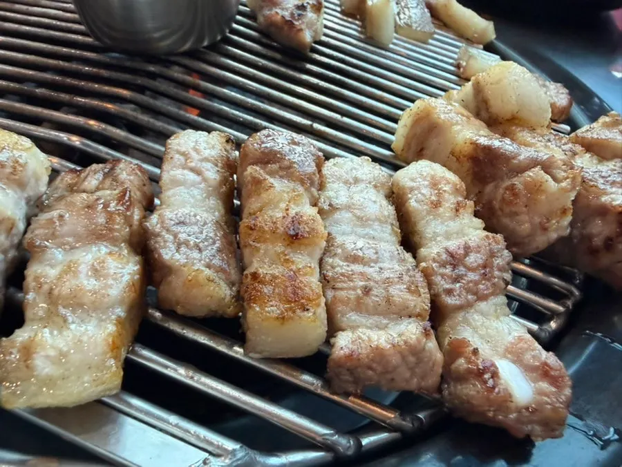 Black pork belly cooking on the grill