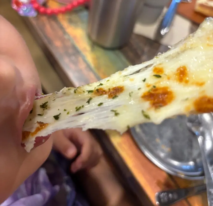 A slice of gorgonzola pizza being dipped in honey