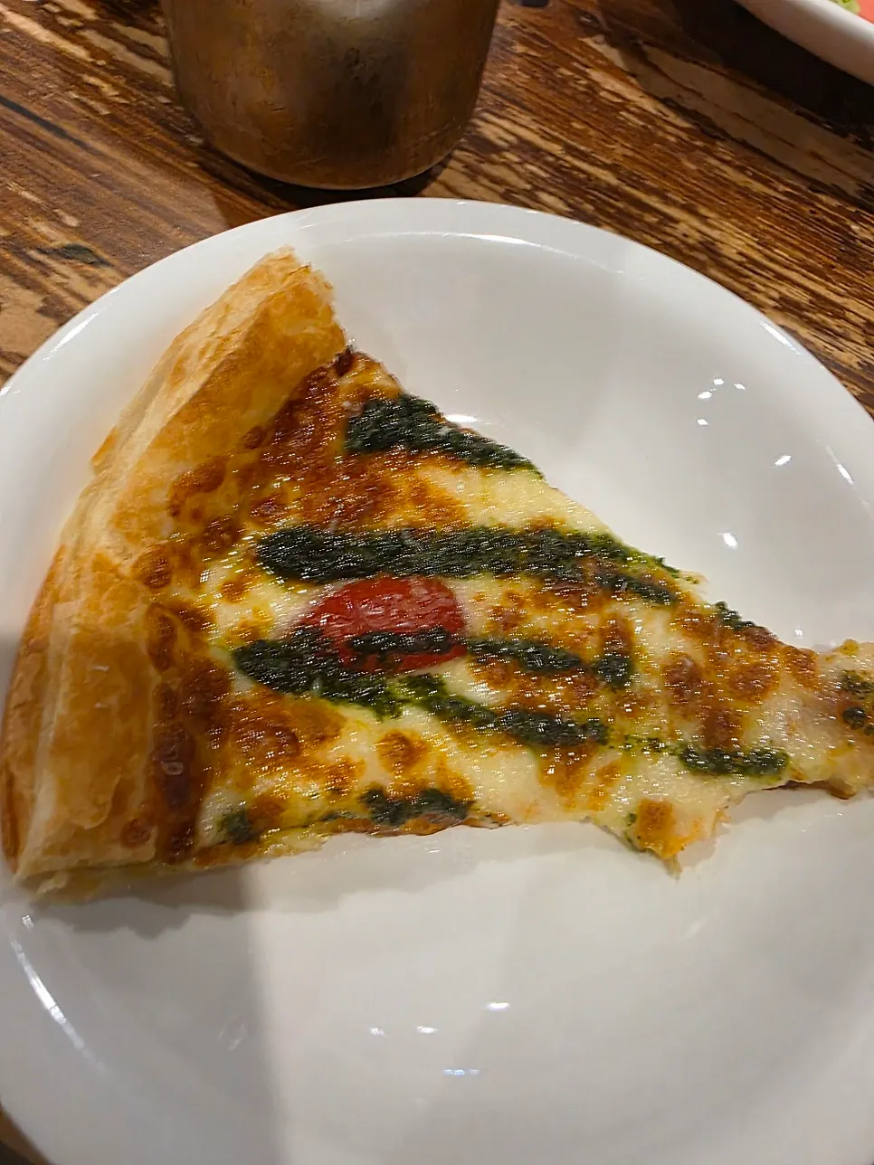 A slice of basil margherita pizza with pastry dough