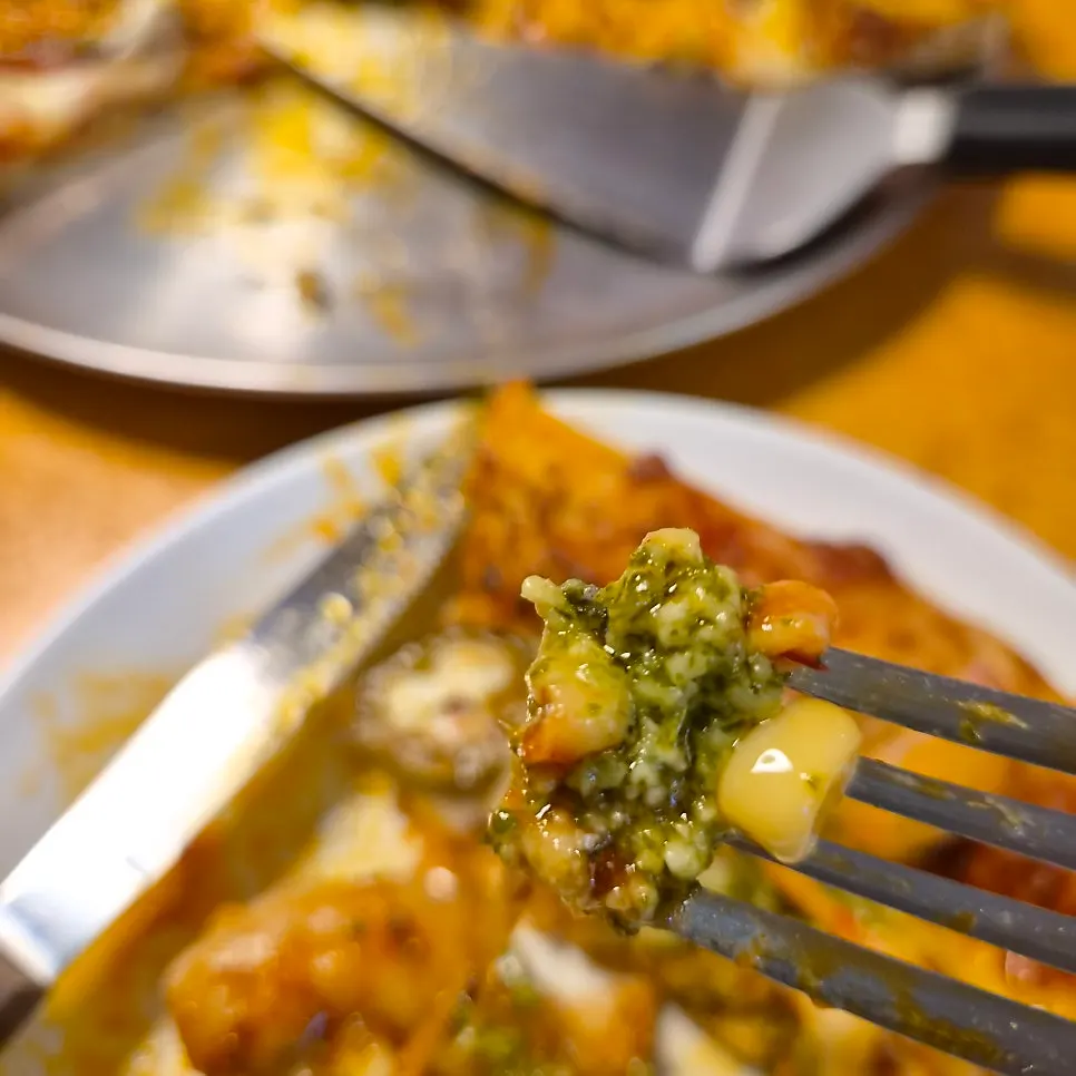 Slice of shrimp pizza topped with cilantro and lime