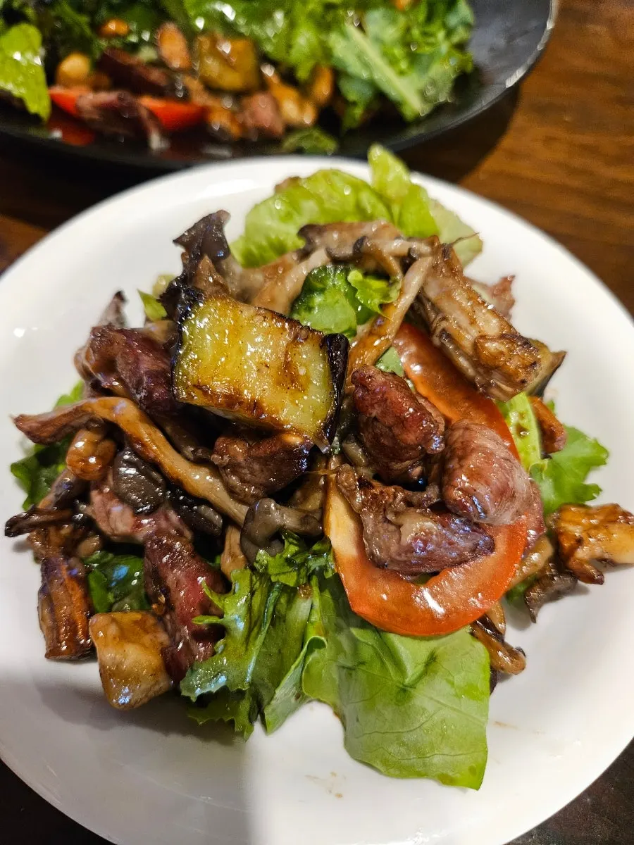 Salad topped with balsamic sauce and stir-fried beef