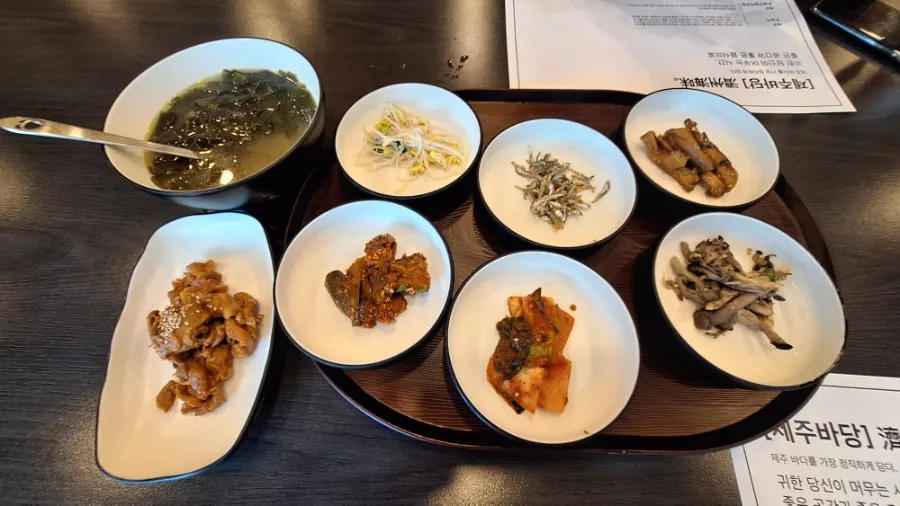 Eight basic side dishes at Jeju Badang, including seaweed soup and stir-fried pork