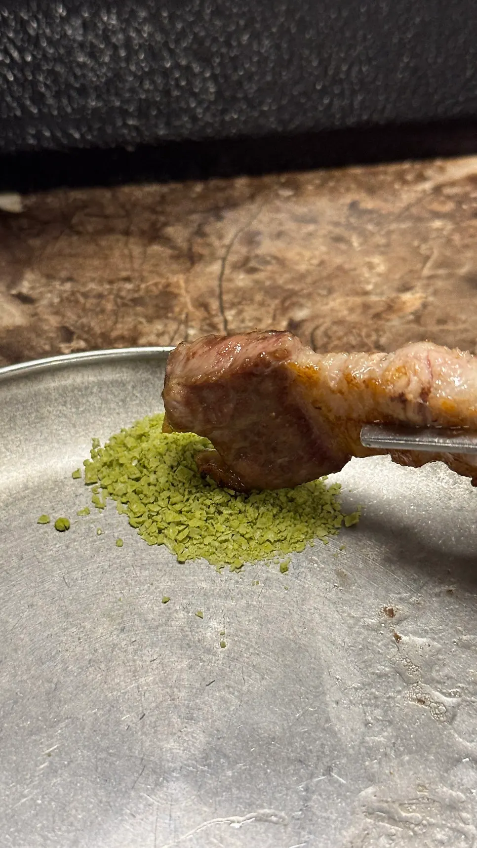 A piece of black pork dipped in matcha salt
