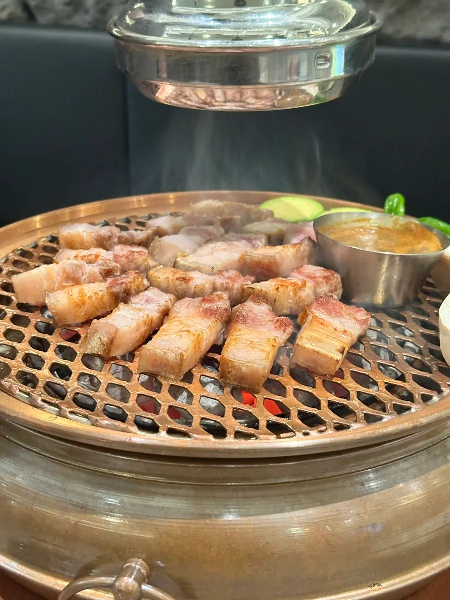 Black pork oegyeopsal placed on the charcoal grill