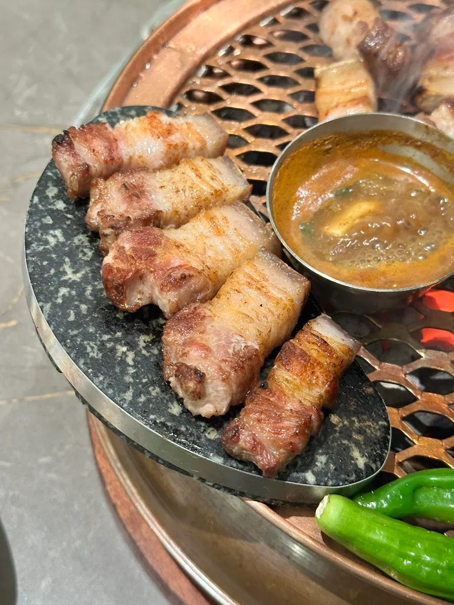 Staff member grilling the black pork oegyeopsal