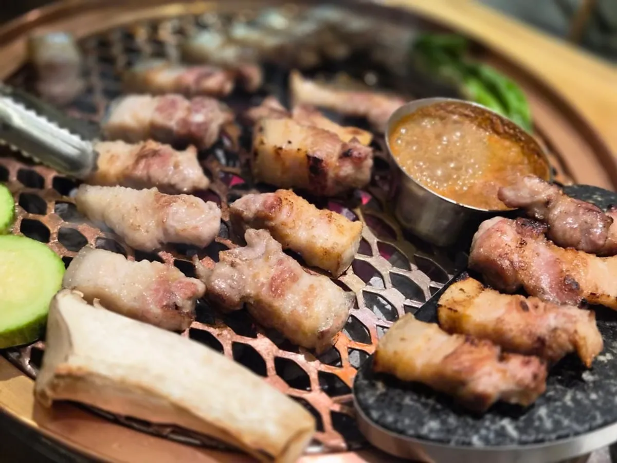 Staff grilling the black pork belly over a charcoal fire