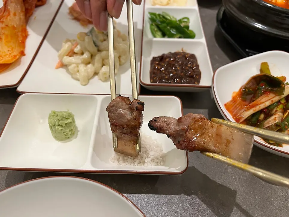 A piece of oegyeopsal about to be dipped in salt