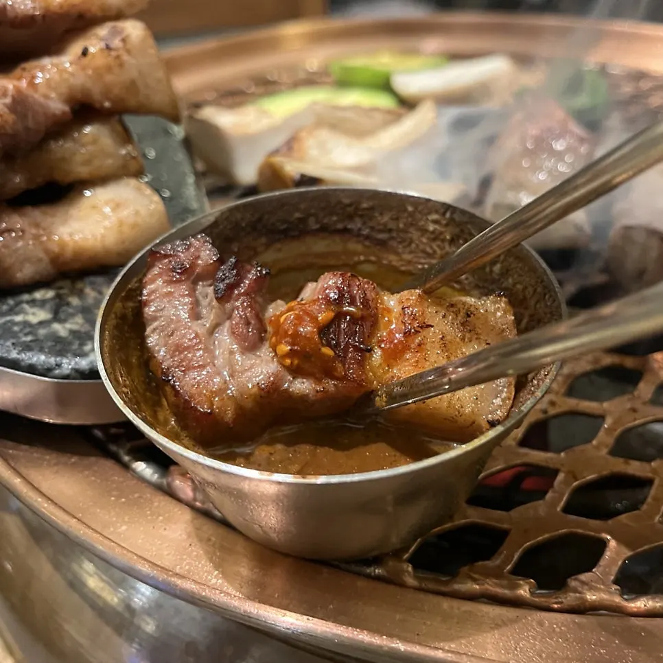 A piece of oegyeopsal dipped in the fermented sauce