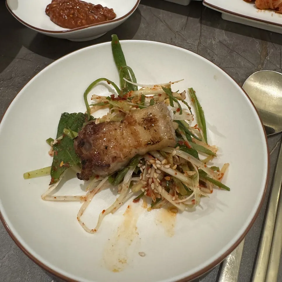 A glass of bokbunja mixed with soju next to grilled oegyeopsal