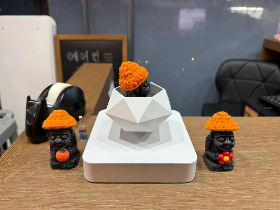간판 아래 현무암 돌담과 밀짚모자 쓴 돌하르방