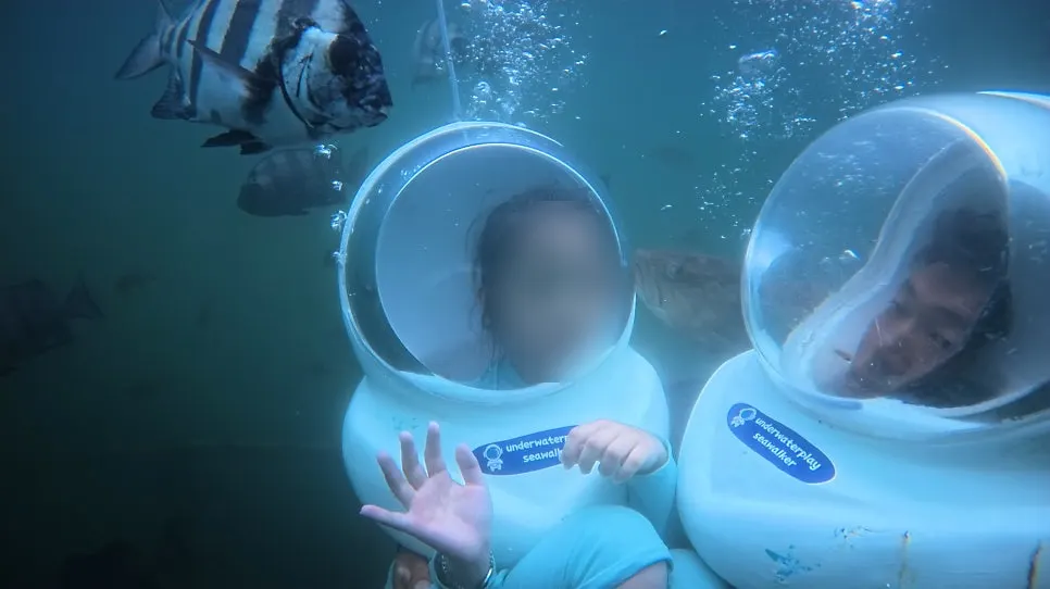 A child wearing a diver helmet descending into the sea