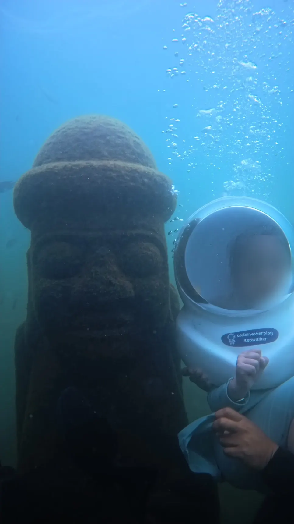 An underwater dol hareubang statue with a helmeted child