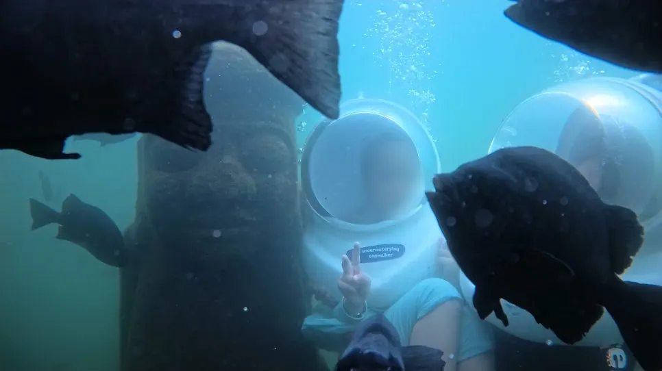 A child posing beside the underwater dol hareubang