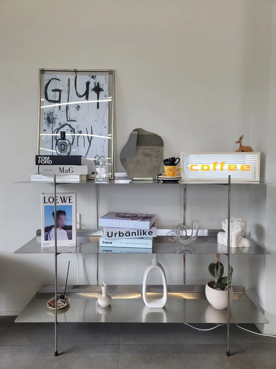 Three-tier steel shelf with art books and ceramic objects
