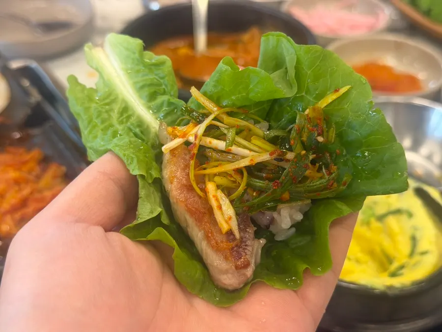 A piece of black pork placed on a lettuce wrap