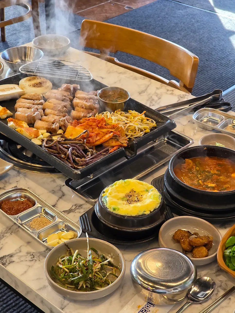 Black pork, kimchi, and vegetables on a stone grill