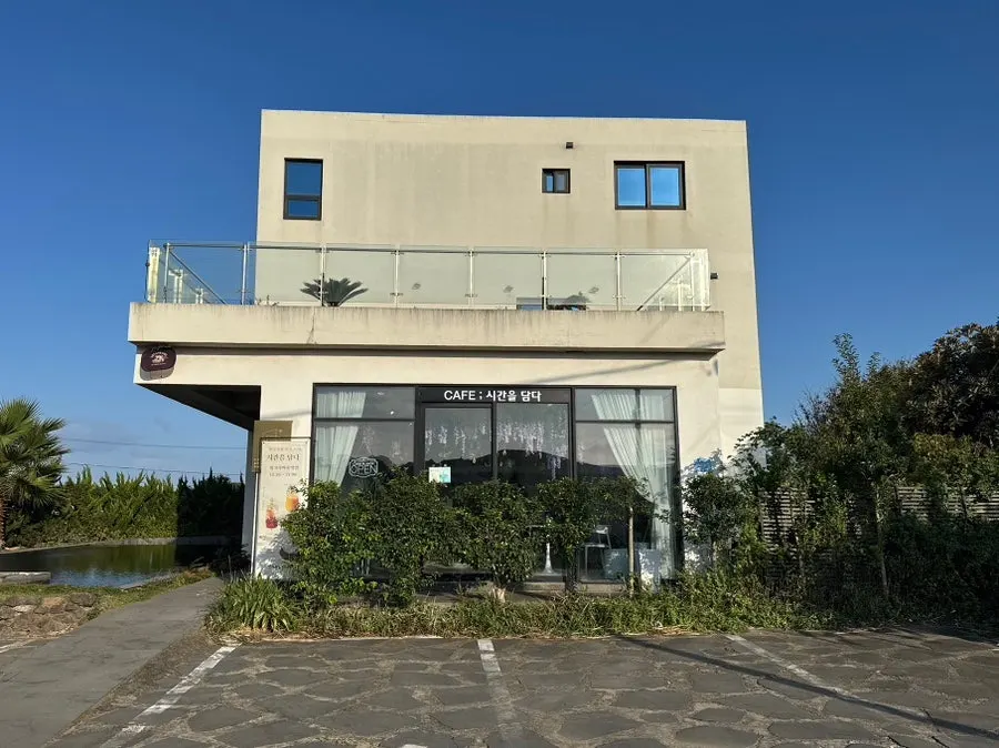 Café exterior with concrete facade, lawn, and long reflection pool