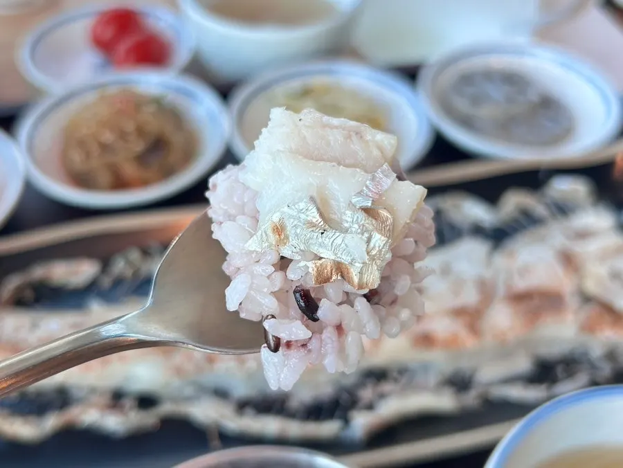 A bite of grilled hairtail-fish eaten with rice