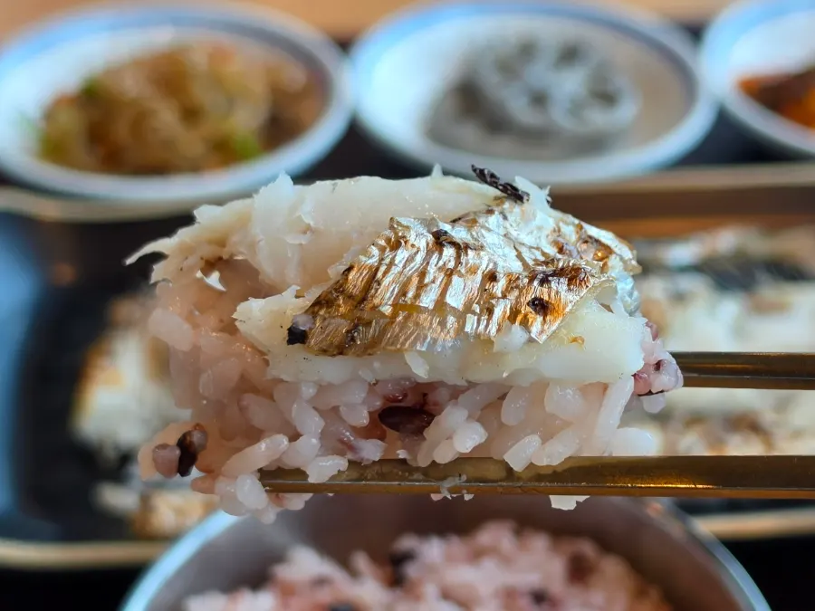 A piece of hairtail flesh lifted with chopsticks