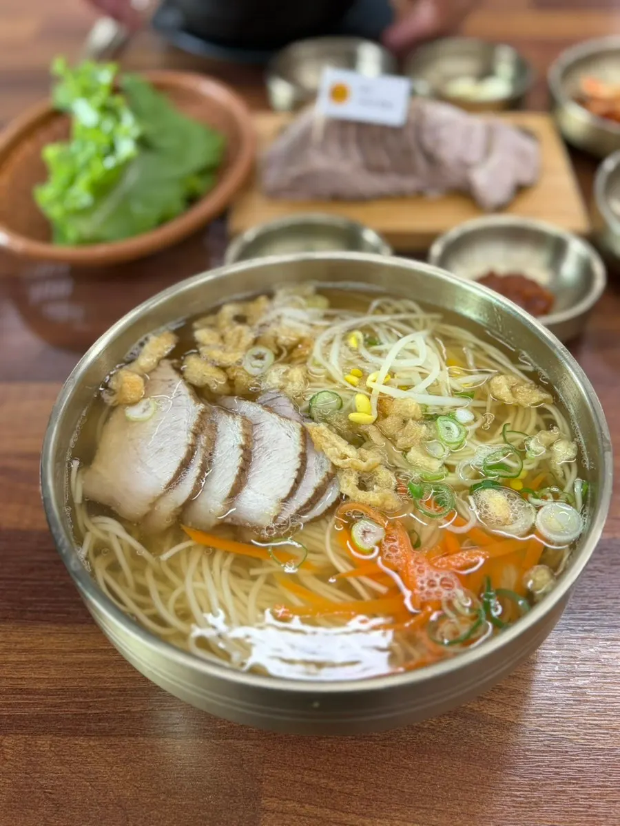 A bowl of myeolgoguksu topped with pork