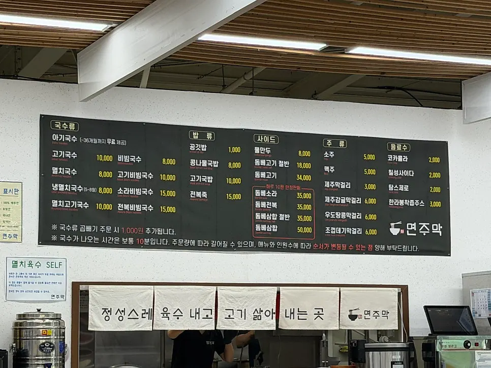 Myeonjumak menu board showing prices for pork noodle soup and dombe pork