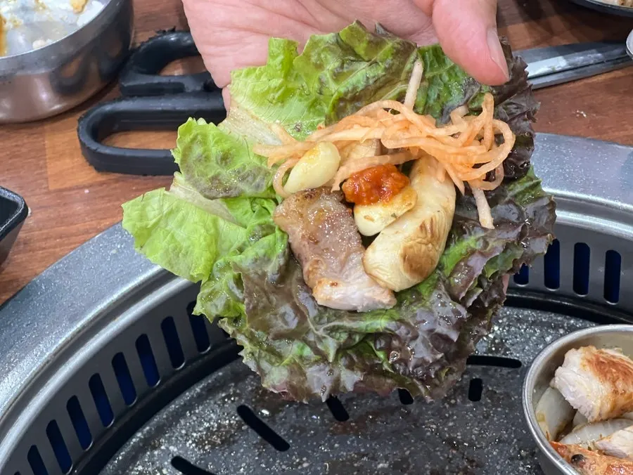 A piece of black pork wrapped in a lettuce leaf