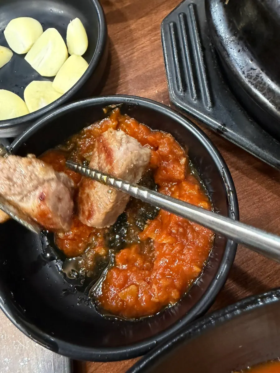 A piece of black pork dipped in salt and ssamjang