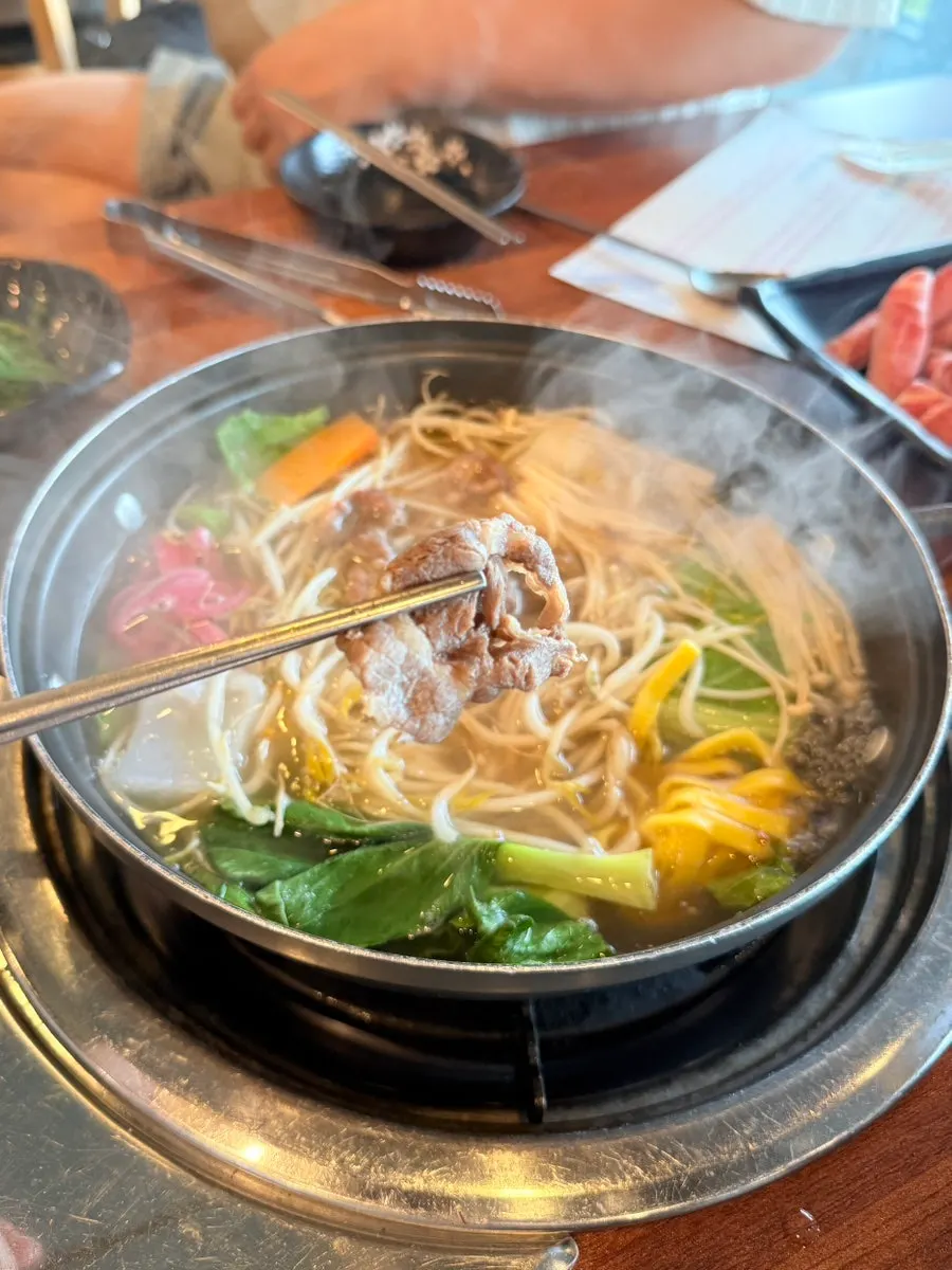 把馬肉放入滾燙湯底涮的樣子