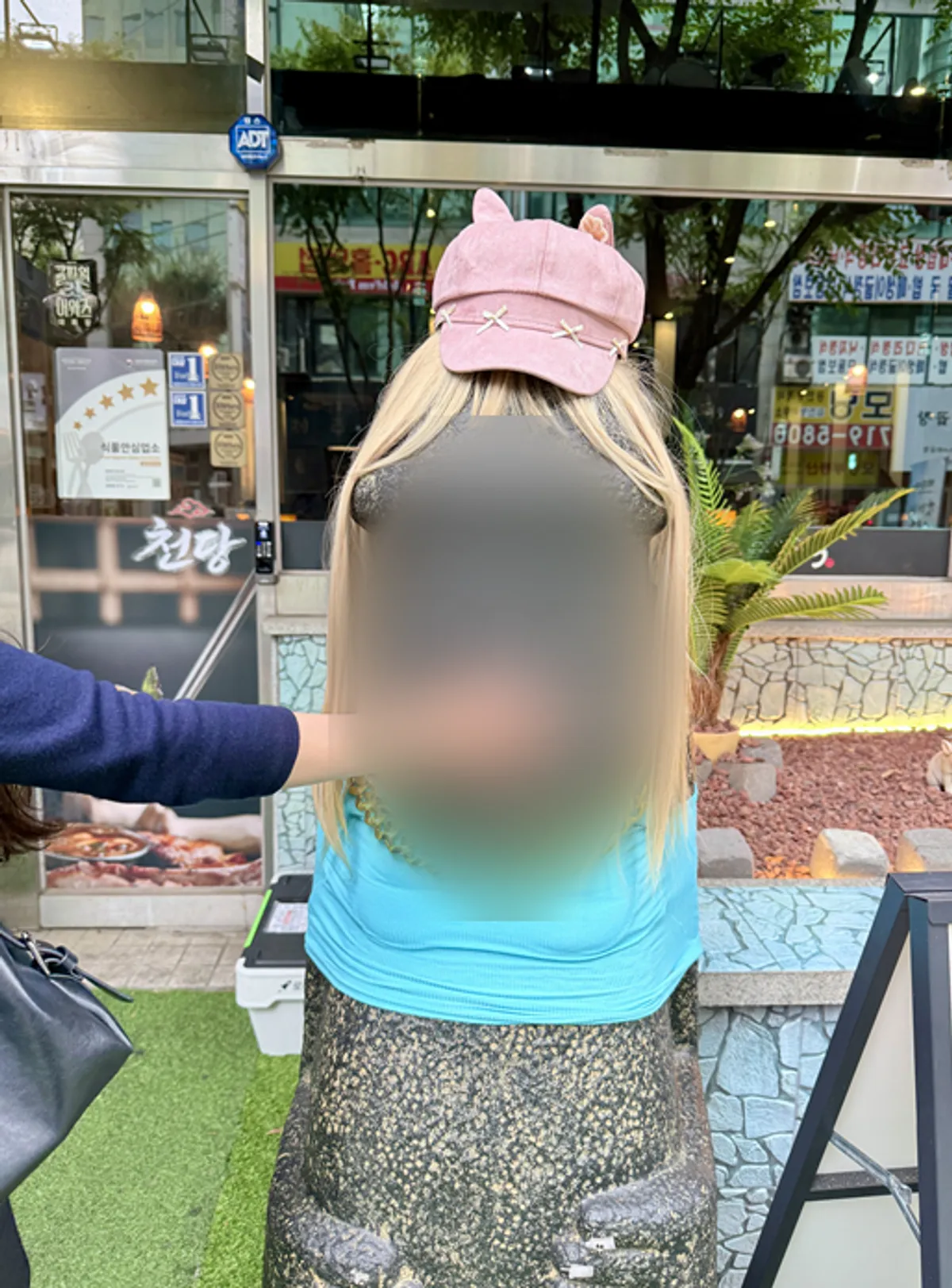 가게 앞 돌하르방 코를 만지는 모습