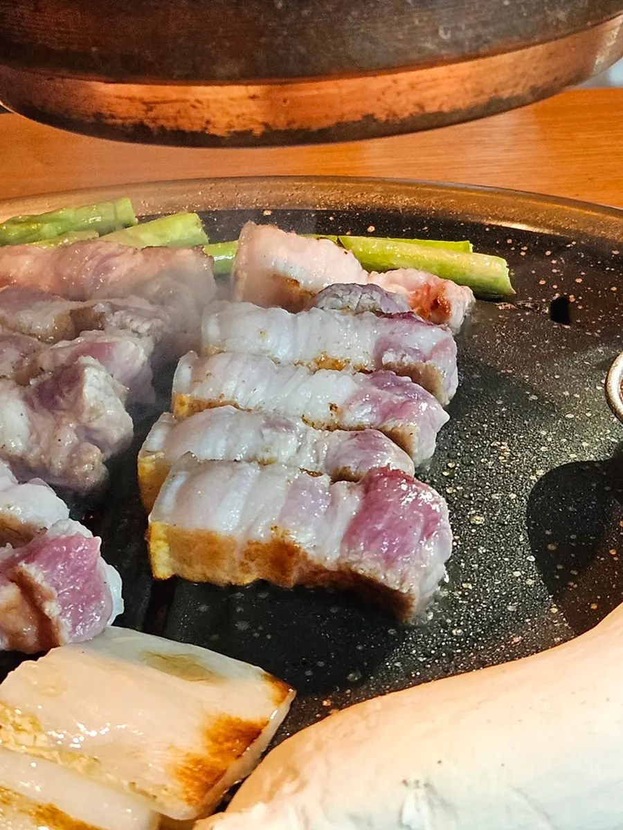 Grill with asparagus and white kimchi cooking alongside the meat