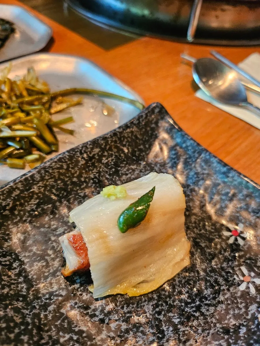 구운 백김치를 올린 흑돼지 한 점