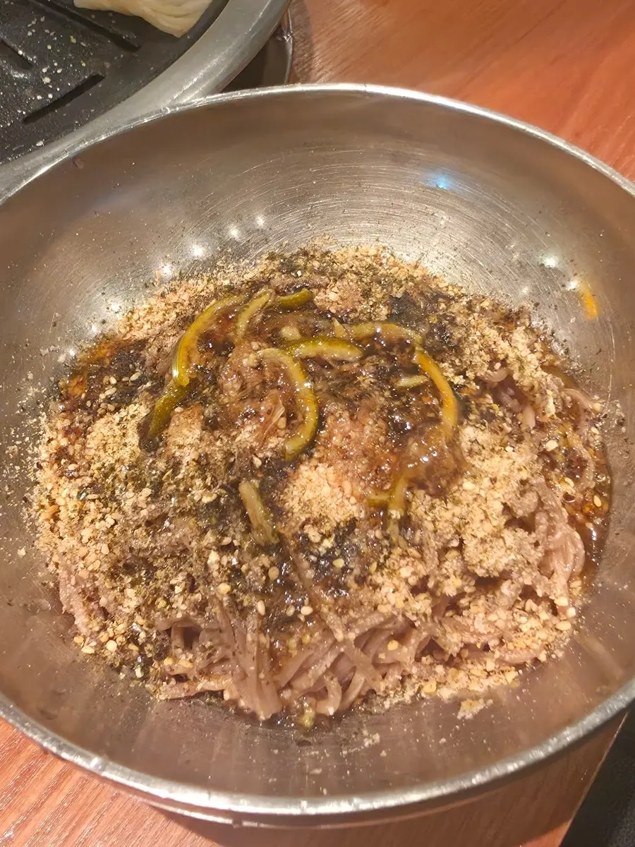 Makguksu topped generously with sesame seeds and powder
