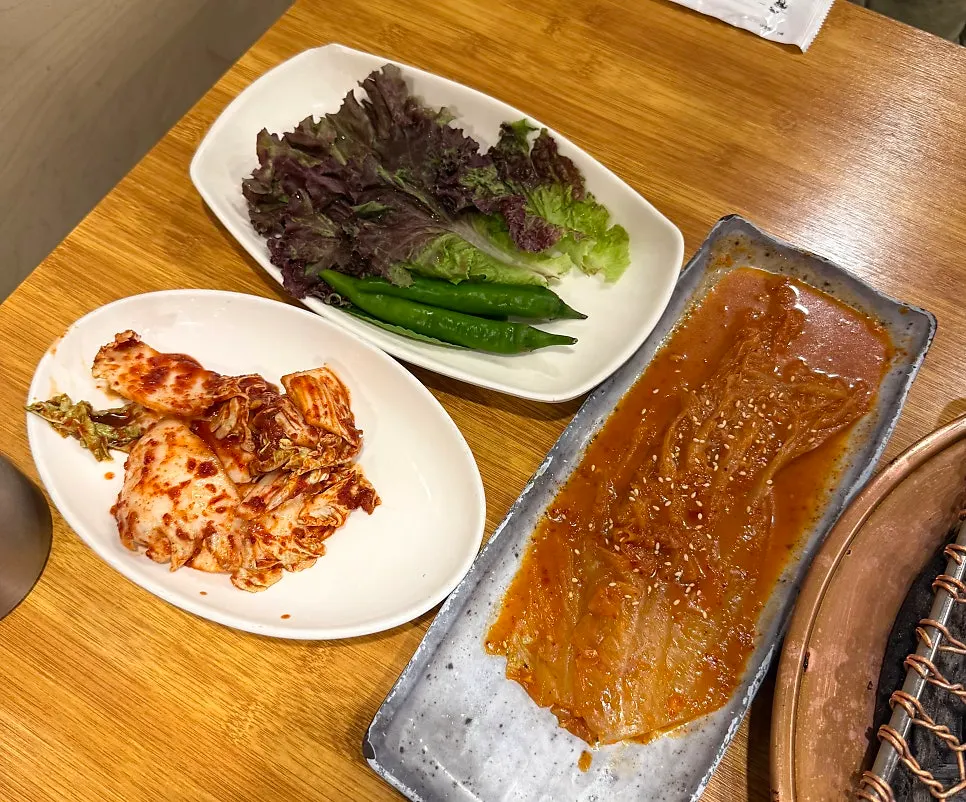 Side dishes including pickled perilla leaves, fresh kimchi, and aged kimchi